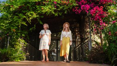 Two women walking under a canopy of leaves into the Mediterranean Biome